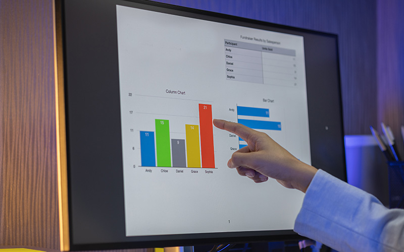 A parent-teacher report view on screen showing a student profile with graphs for attendance, grades, and a “Download Report” button