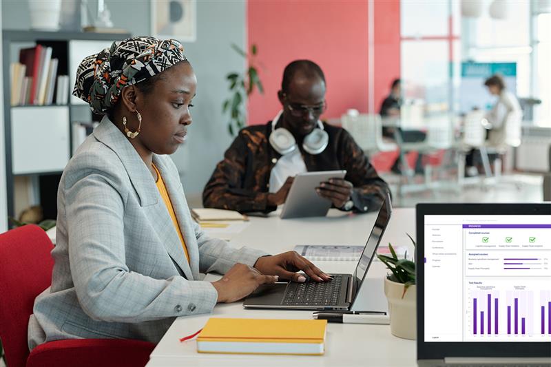 Employee working on a laptop with analytics dashboard on screen, demonstrating how LMS for employee training provides performance insights.
