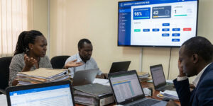 University admissions office with staff reviewing multiple applications across spreadsheets, emails, and paper files, visible confusion and delays, contrasted subtly with a centralized digital admission dashboard on a large screen showing university admission challenges