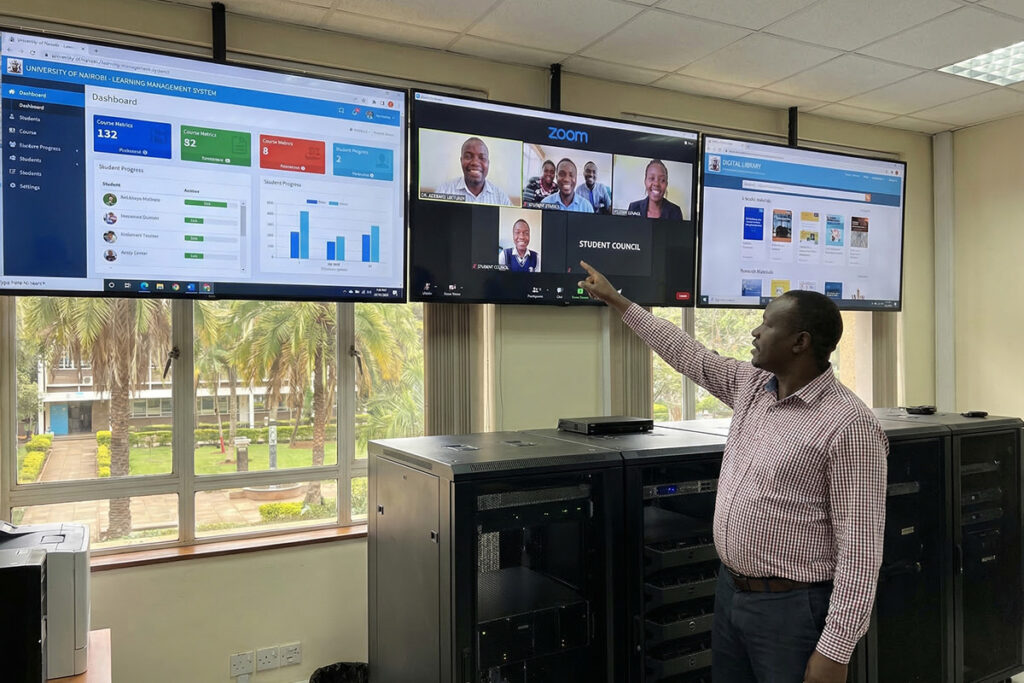 hybrid learning in universities IT setup with LMS dashboard, video conferencing system, and digital content platform displayed on multiple screens